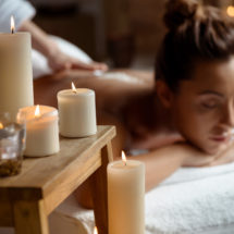 Young beautiful girl relaxing in spa salon. Focus on candles.